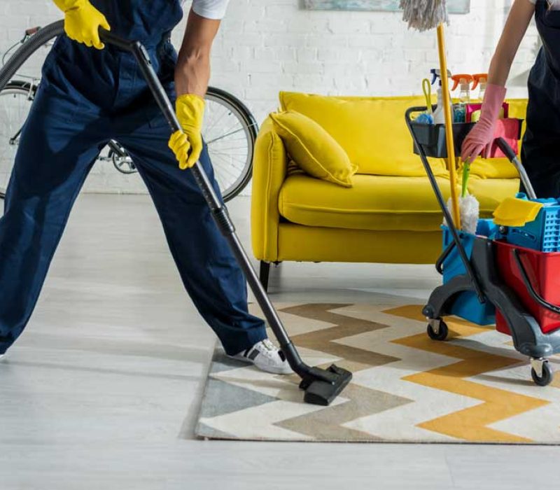 cropped-view-of-cleaners-in-overalls-cleaning-apar-XXJP3SX